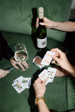 Friends playing cards over a bottle of wine